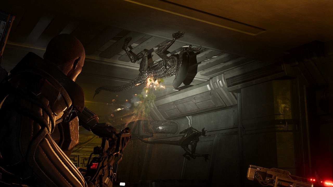 A Marine fires at Xenomorphs crawling across the ceiling
